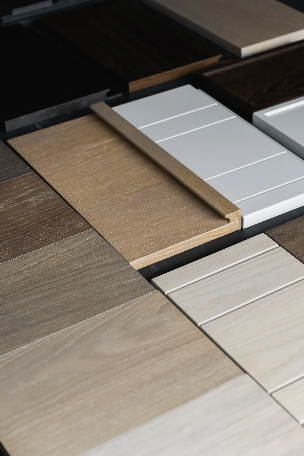 A variety of wood laminate flooring samples in different shades and finishes, arranged in a grid.