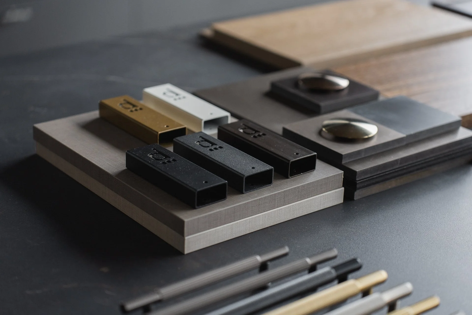 Various color sample tiles with metallic and matte finishes on a dark surface, surrounded by sorted colored rods.
