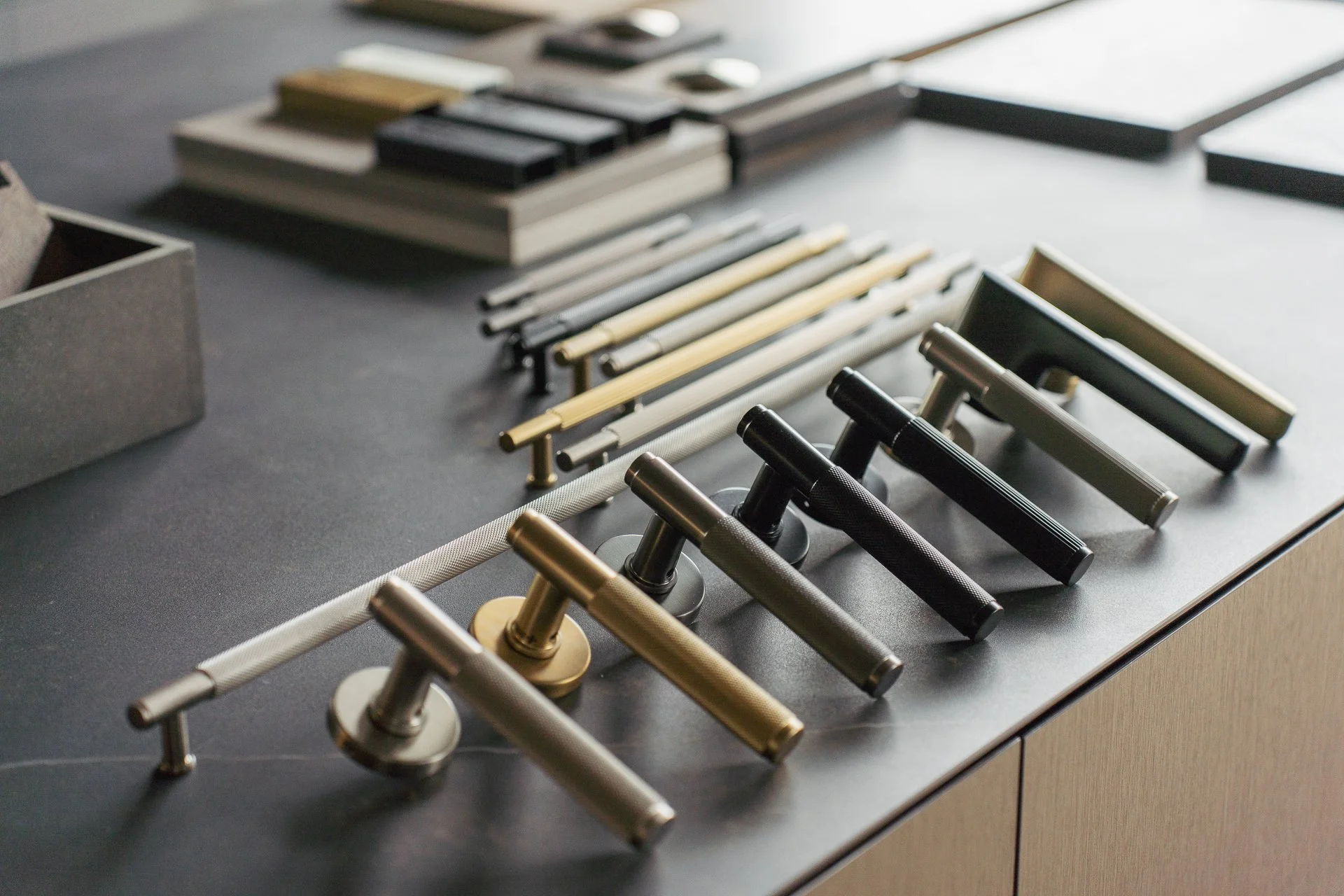 A display of various door handles and pulls arranged on a table.