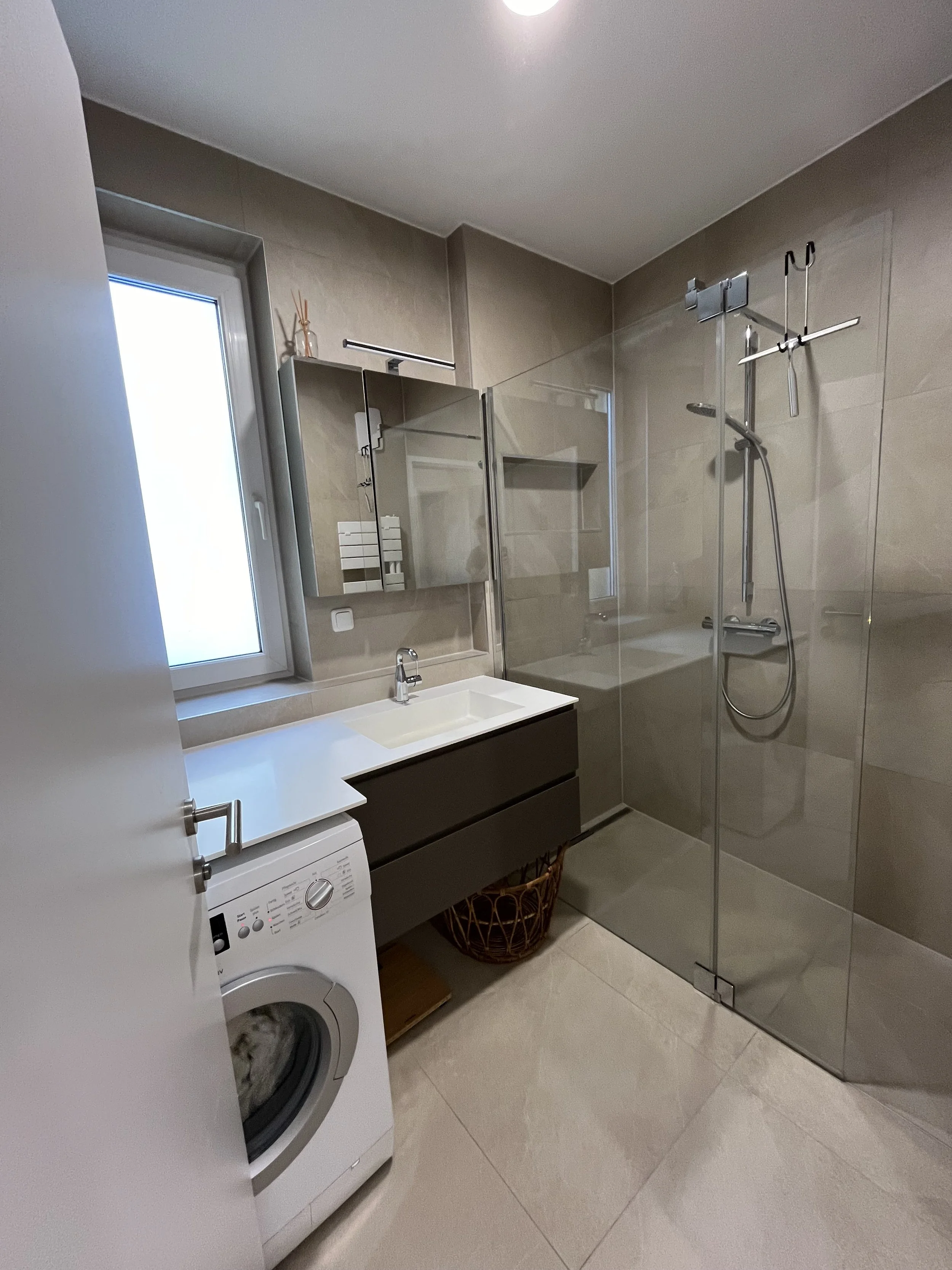 Modernes Badezimmer mit Dusche, Waschbecken und Waschmaschine.