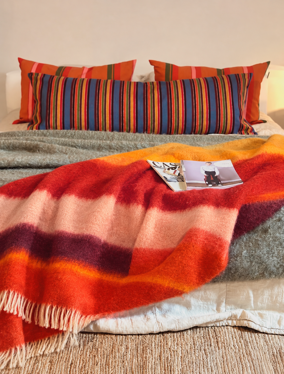 Gemütliches Bett mit farbenfroher Wolldecke.png