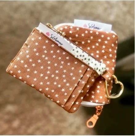 A small brown wallet with white stars, a matching coin pouch, and a white chopstick with black stars, all attached to a key ring.