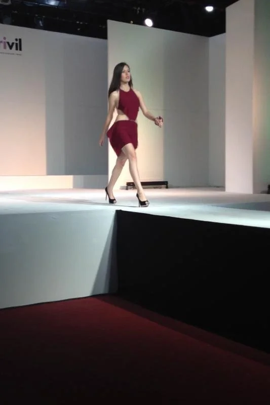 A woman walking on a fashion runway stage.