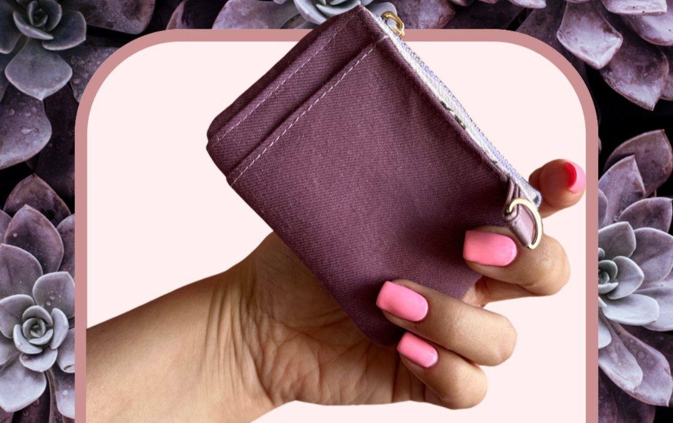 A person holding a small maroon wallet against a background of purple succulents.