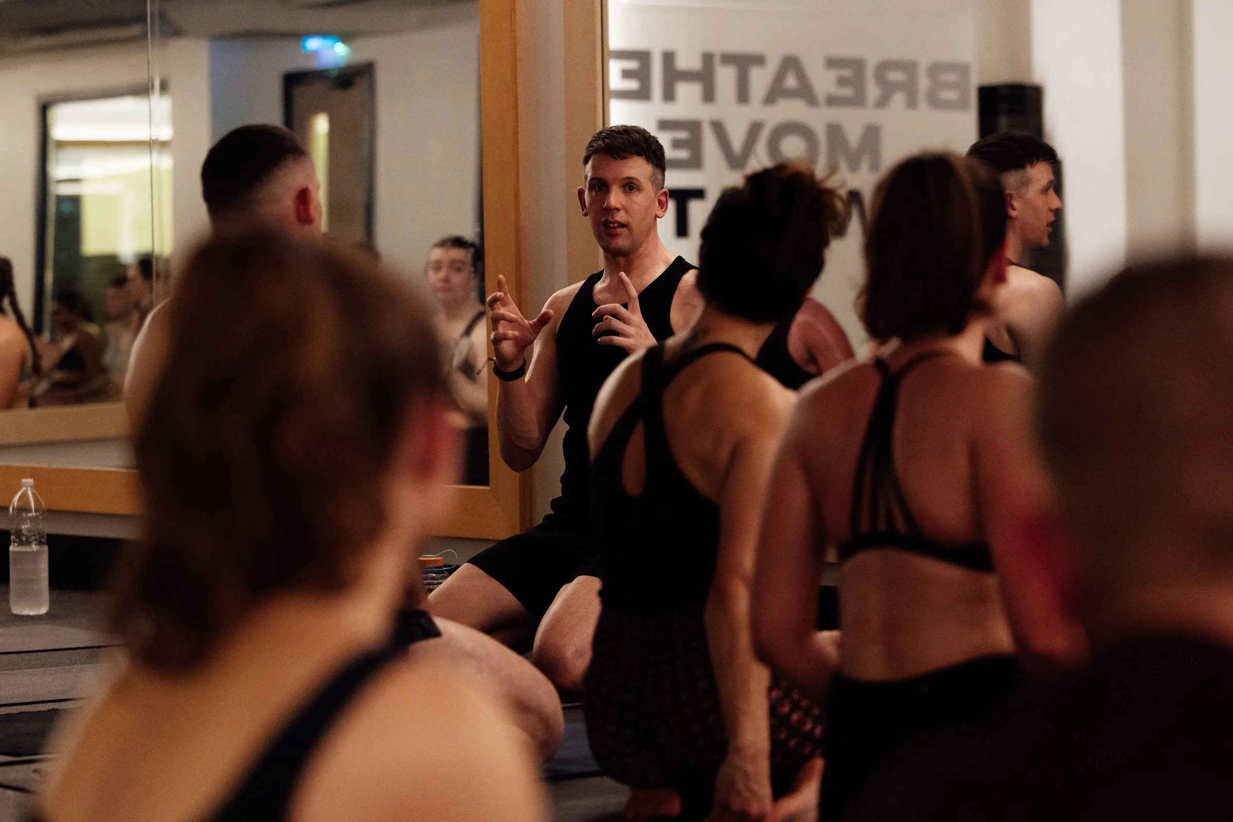 Group of women participating in a yoga class, kneeling on mats, with one woman smiling at the camera.