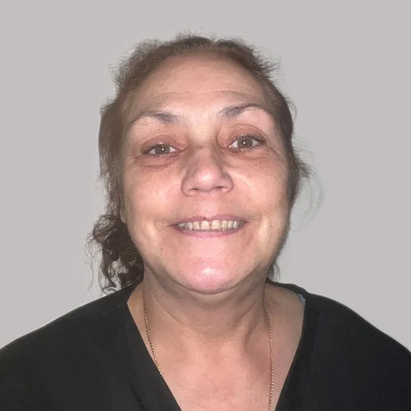 Smiling middle-aged woman with brown hair and a black shirt against a plain gray background.