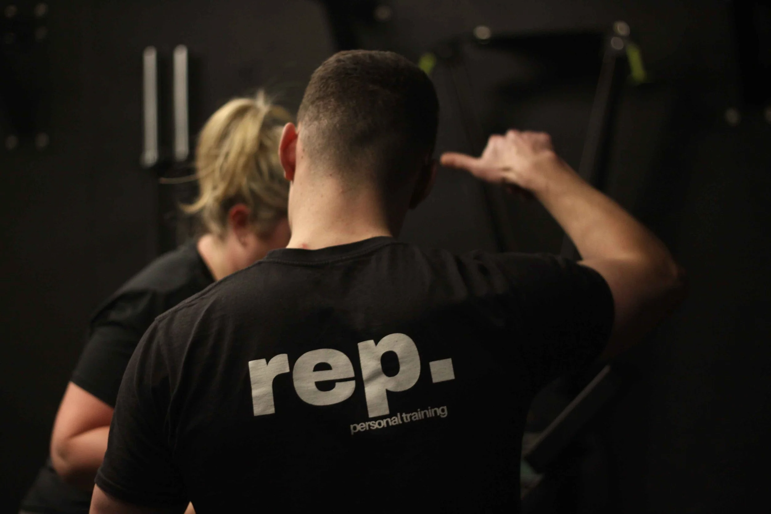 Personal trainer giving instructions to a client during a workout session in a gym.