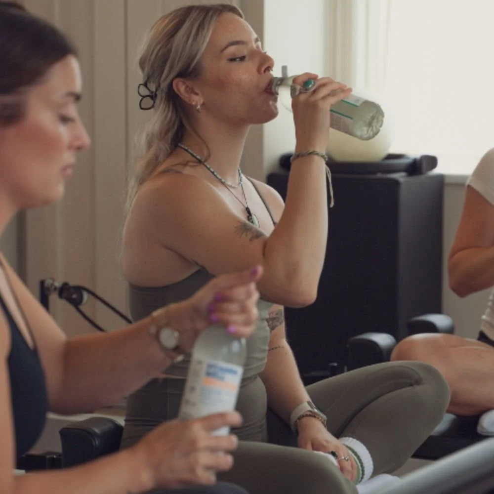 Clients pausing to hydrate during a reformer class at Sojourn Pilates studio.
