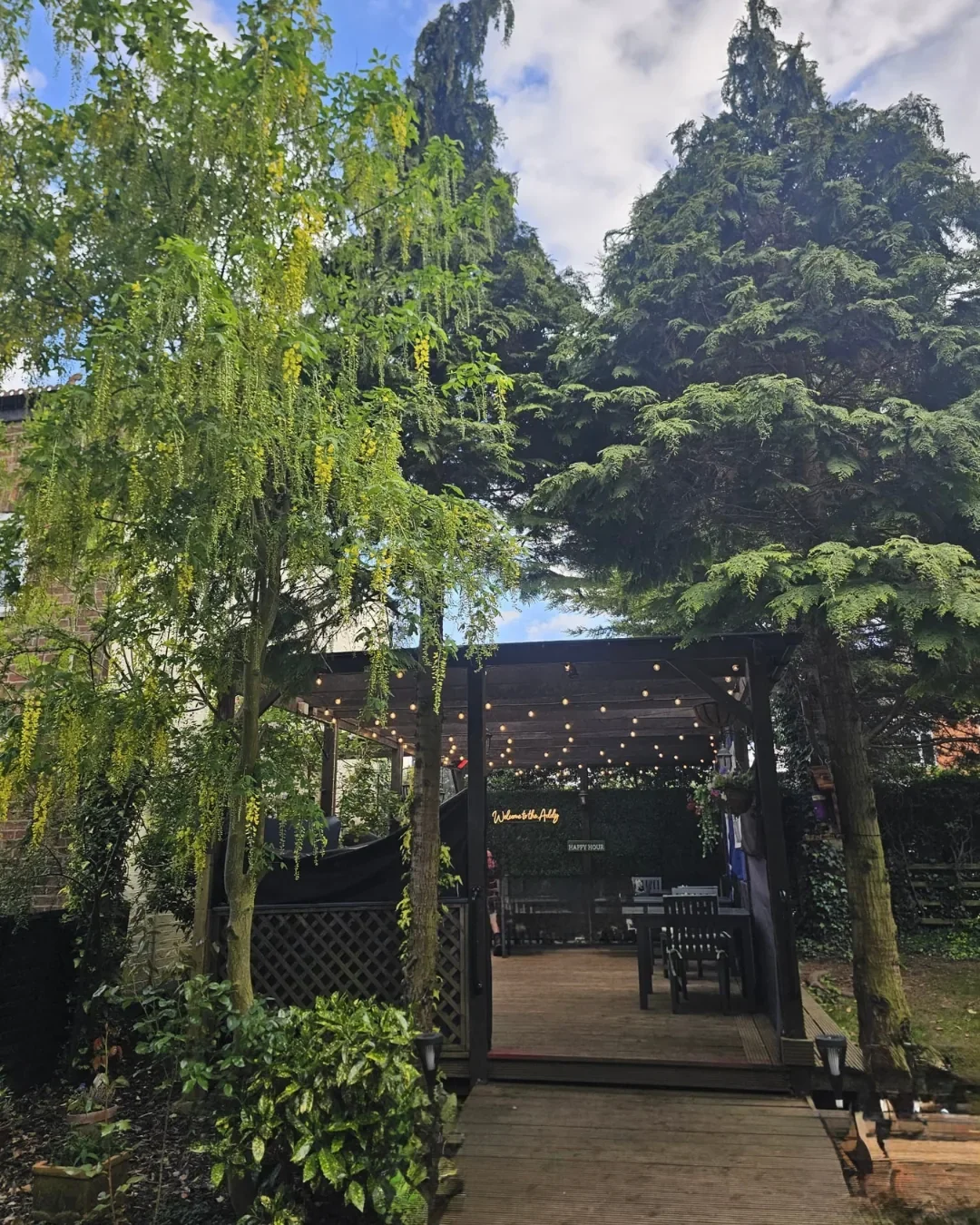 Pergola and festoon-lit garden decking at The Red Admiral pub in Broughton Astley, where outdoor mat Pilates and brunch take place for the Sojourn Summer Social.