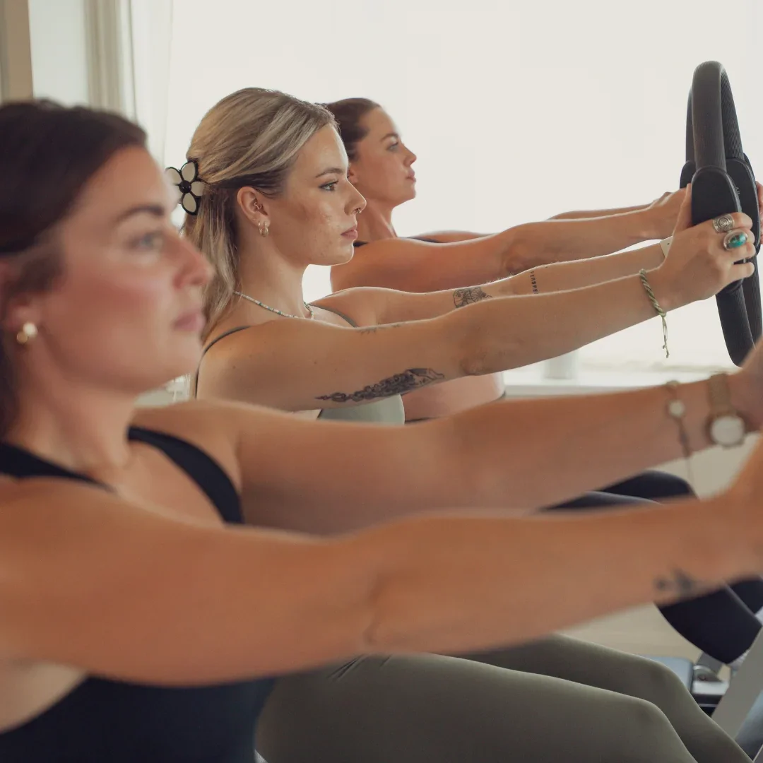 Three clients side-by-side on reformers in the Sunday Basics class, the beginner reformer Pilates class at Sojourn Pilates in Leicestershire.
