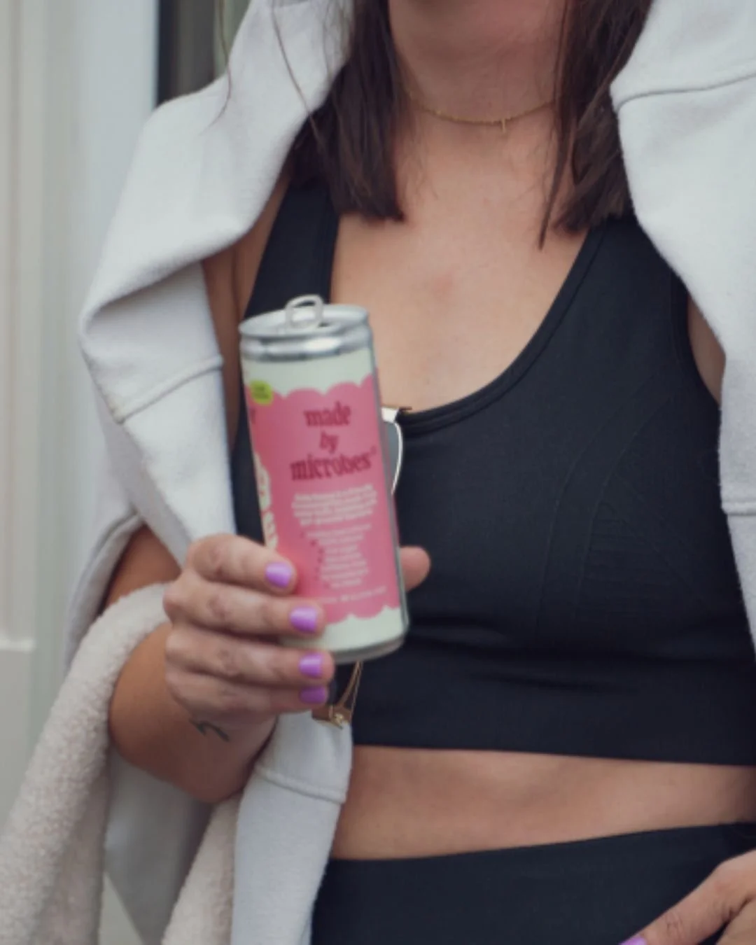 Sojourn Pilates client holding a Belly Dance Kefir Soda drink outside the studio after class.
