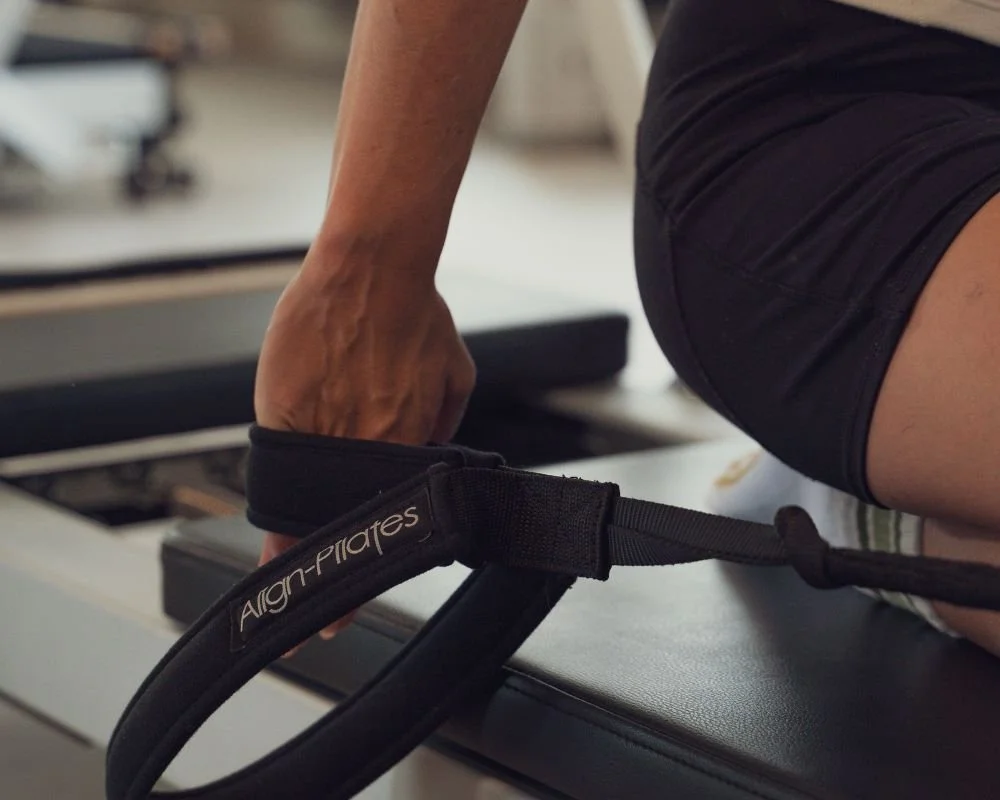 Close-up of a hand holding the reformer strap during a Sojourn Ignite class in Leicestershire.
