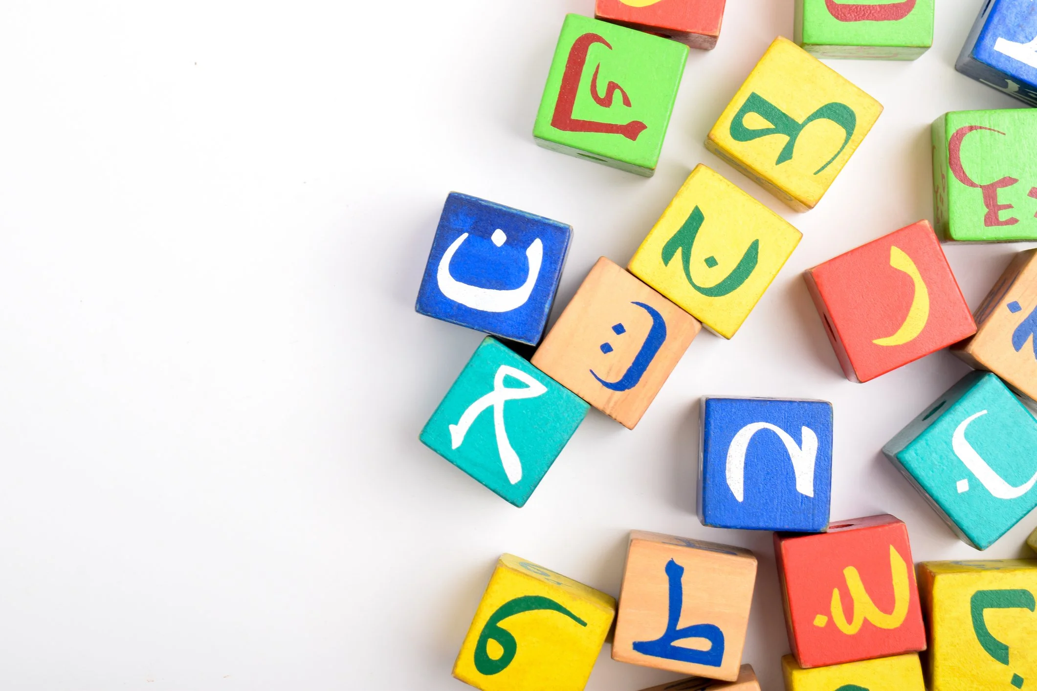 Bunte Würfel mit arabischen Buchstaben und Smileys auf weißem Hintergrund.
