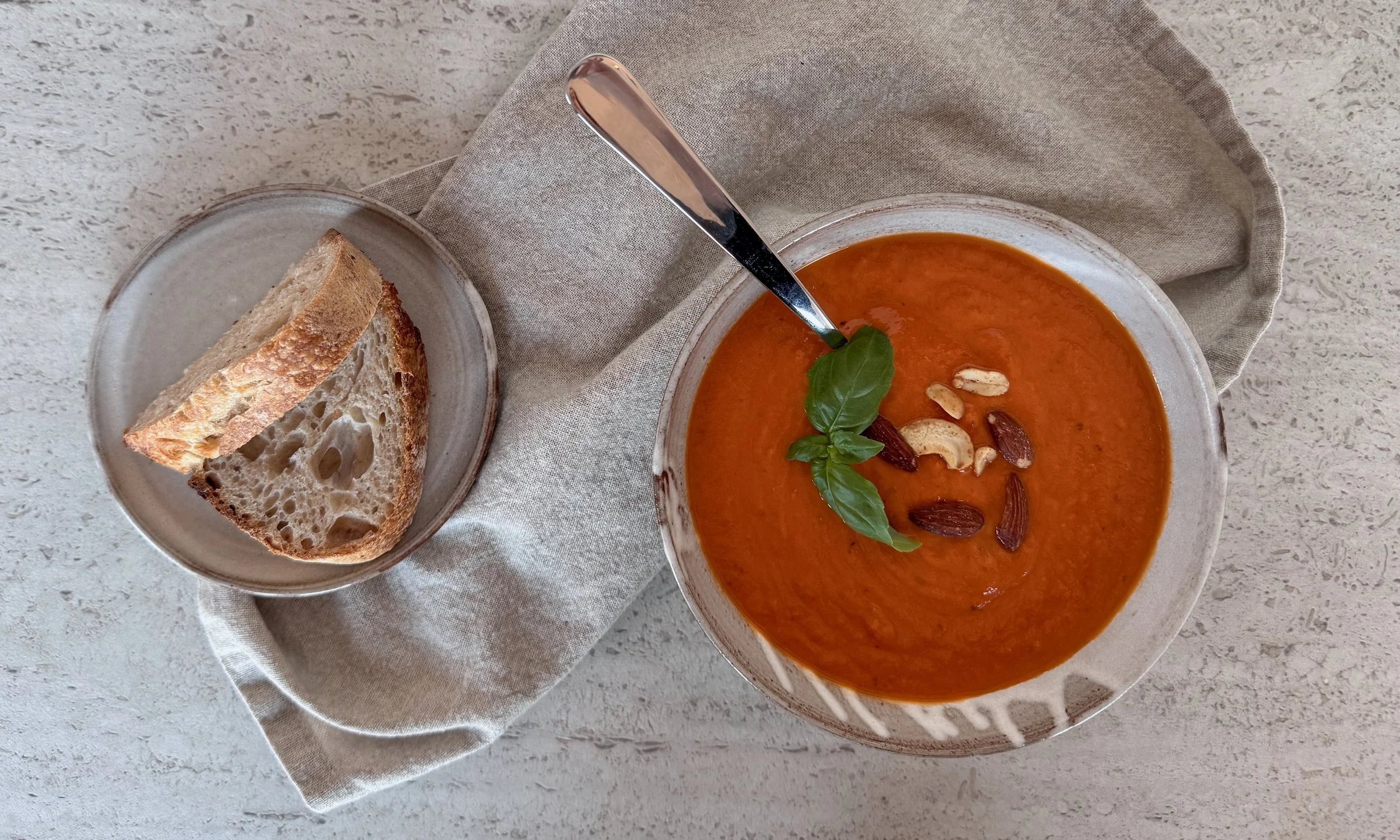 a handmade bowl full of soup and a small handmade plate with bread