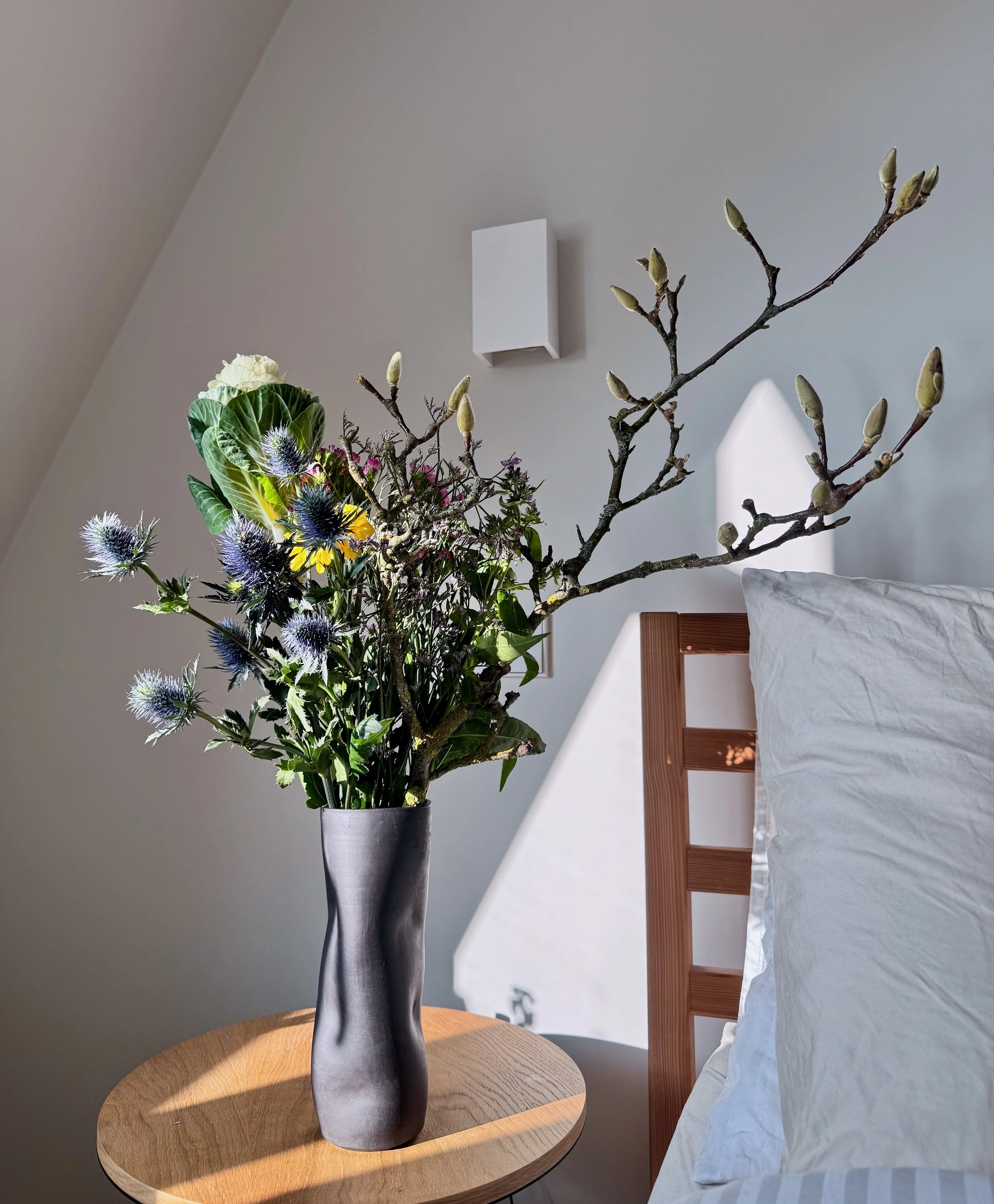 a handmade vase in black matte exposed clay and wobbled shape