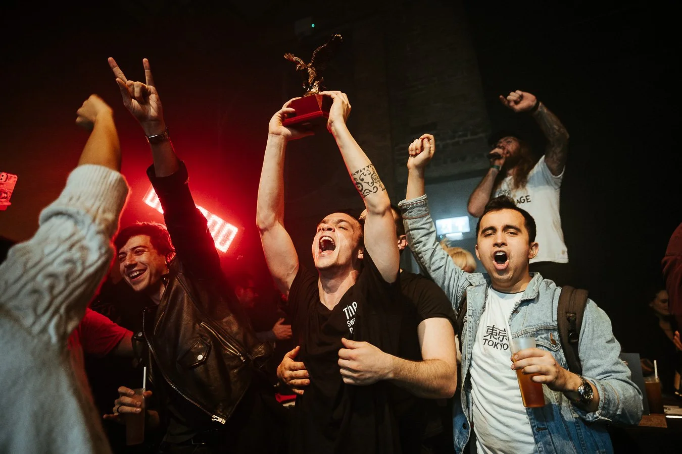 Group of people celebrating at a concert, with one person holding a trophy/award above their head.