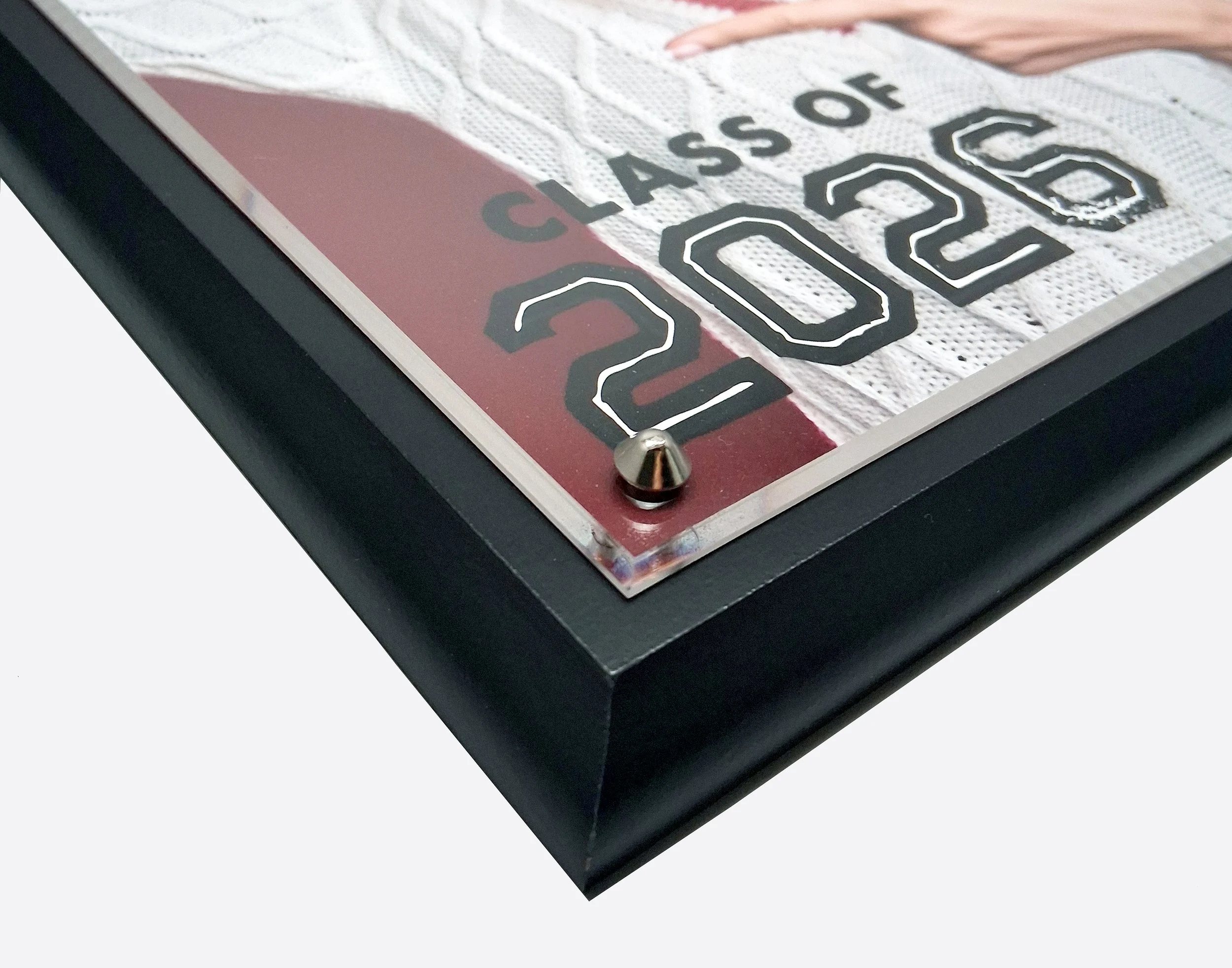 Close-up of a wall clock displaying the time 2:15. The clock has a black frame, black hands, and is mounted on a tiled wall with the words "CLASS OF 2020" visible.
