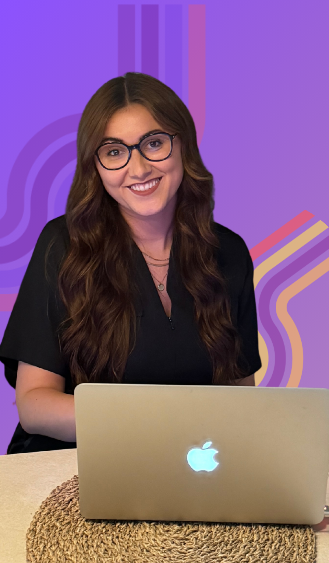 A woman with long brown hair, glasses, and a black shirt sitting at a table with a silver Apple MacBook. The background is purple with abstract colorful lines.