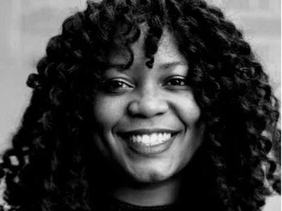 Close-up portrait of a woman with curly hair, smiling. Muma Sinkala