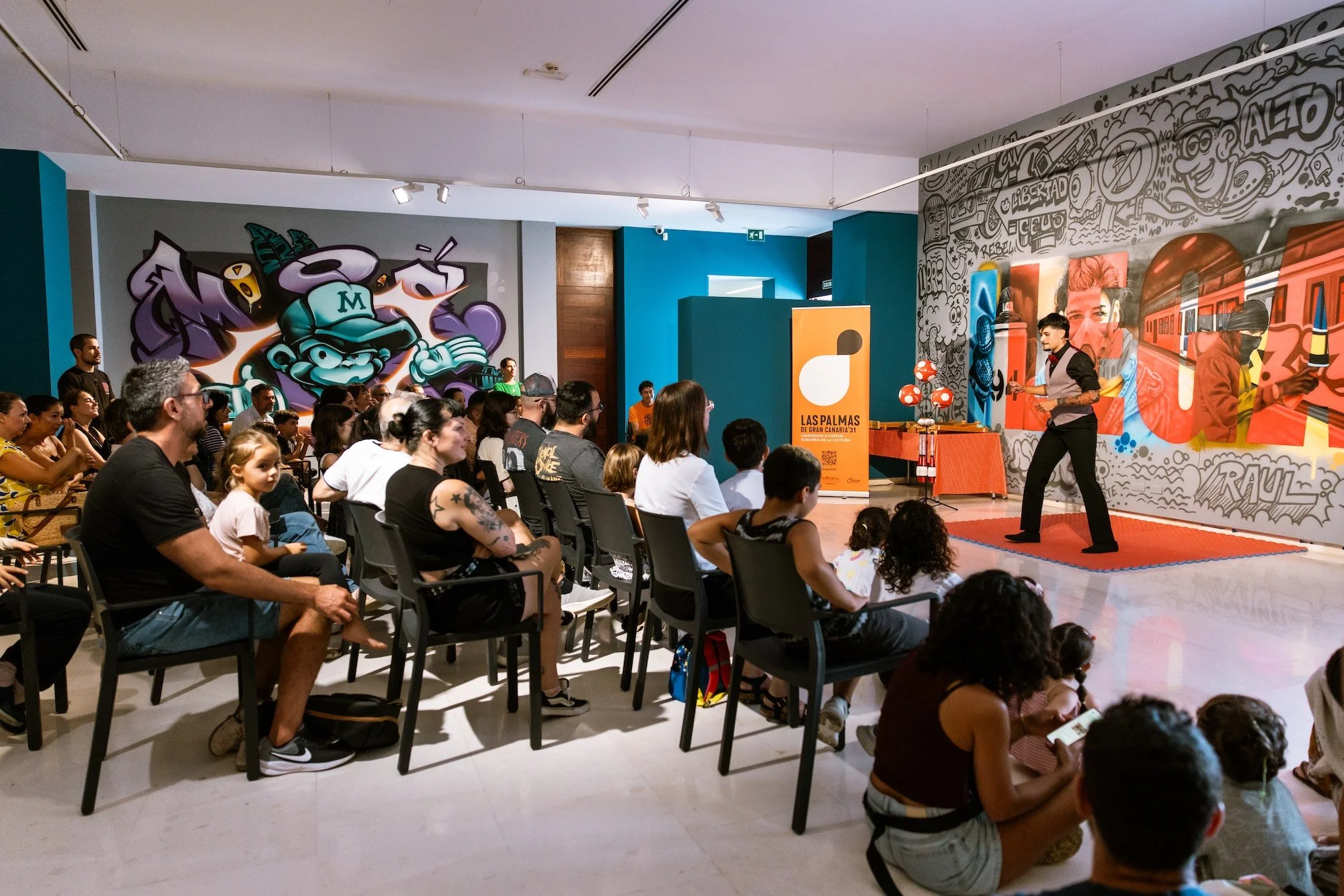 Familias y público de todas las edades observan una actuación circense durante la jornada de dinamización familiar en el Museo Castillo de Mata