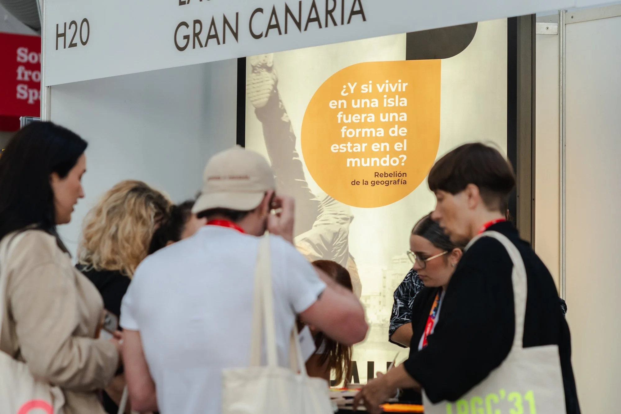 Visitantes se acercan al stand de Las Palmas de Gran Canaria en WOMEX 2026, con un cartel naranja que pregunta ‘¿Y si vivir en una isla fuera una forma de estar en el mundo?