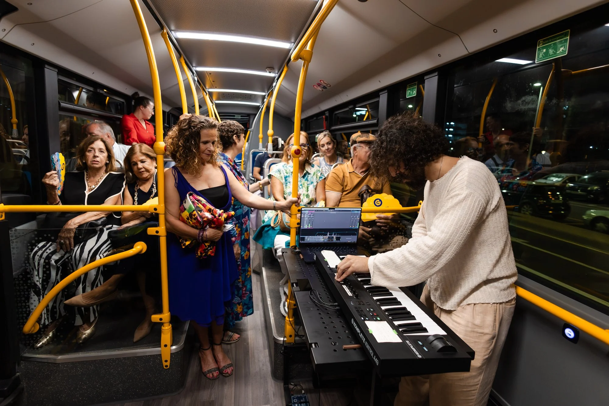 Un músico toca el teclado para los pasajeros de una guagua municipal, de camino al Concierto de Contenedores en el Puerto de La Luz
