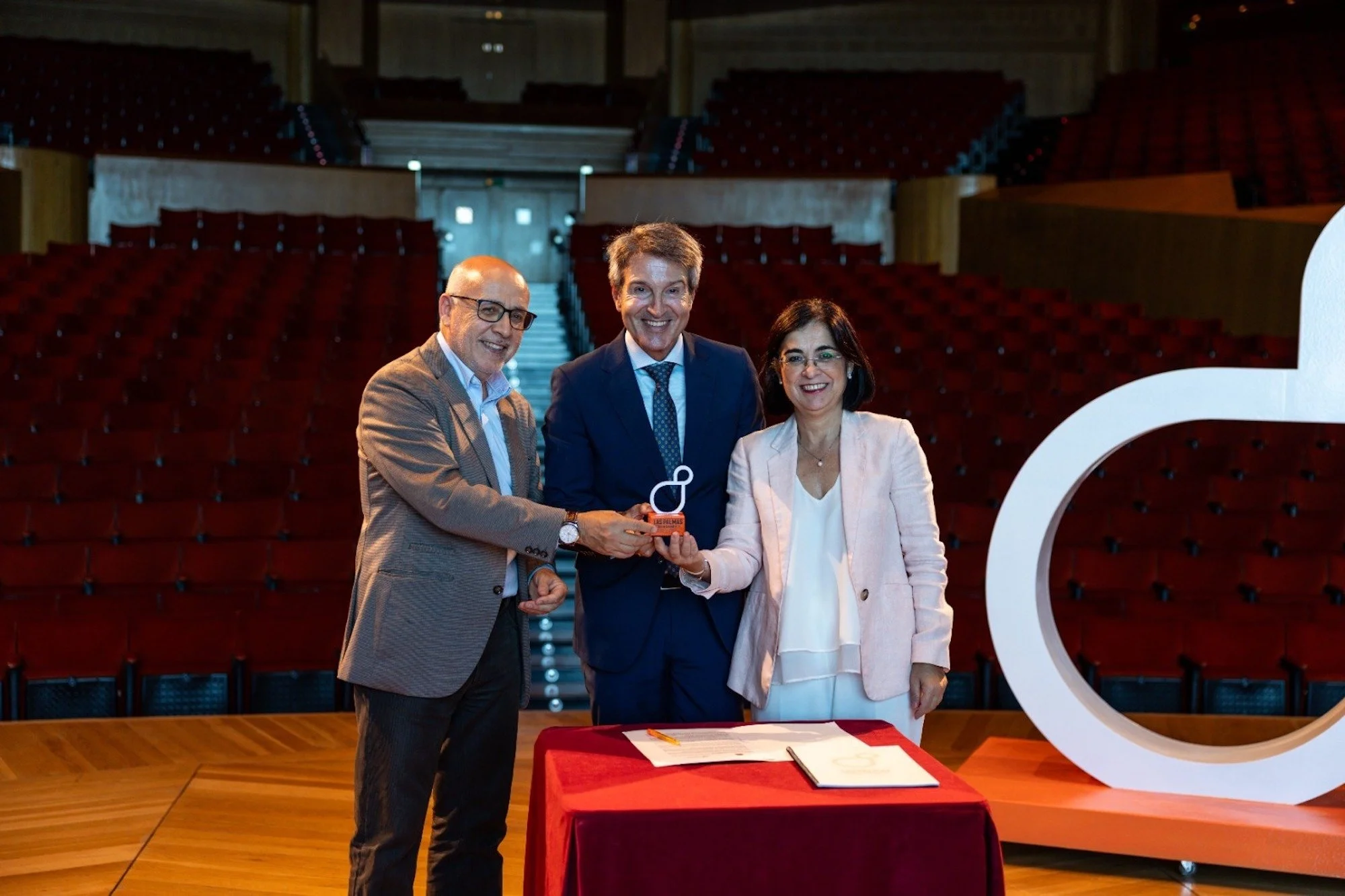 Antonio Morales, Zoilo Alemán y Carolina Darias posan en el escenario del Auditorio Alfredo Kraus sosteniendo la escultura del símbolo de LPGC'31