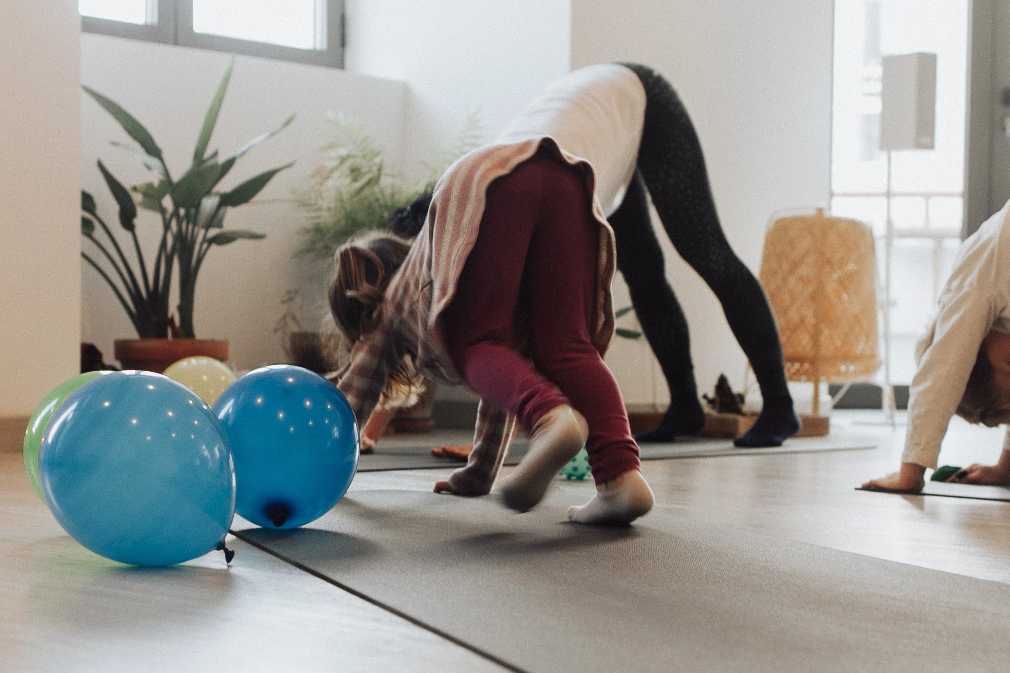 Children participating in a yoga or exercise class indoors with balloons on the floor.