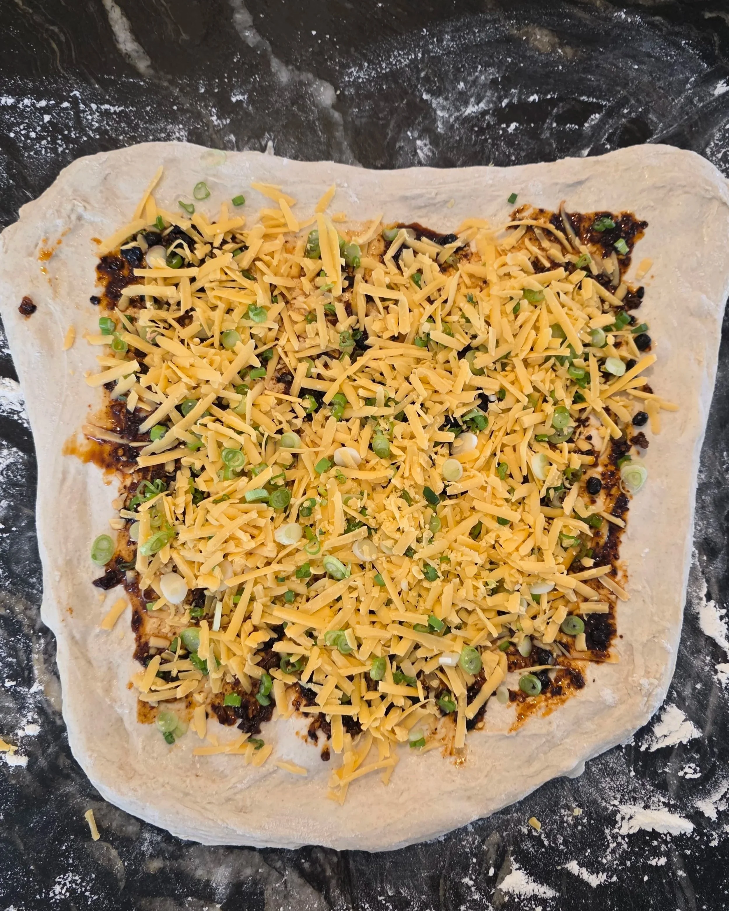 Sourdough lamination process with cheddar cheese and scallions spread on dough