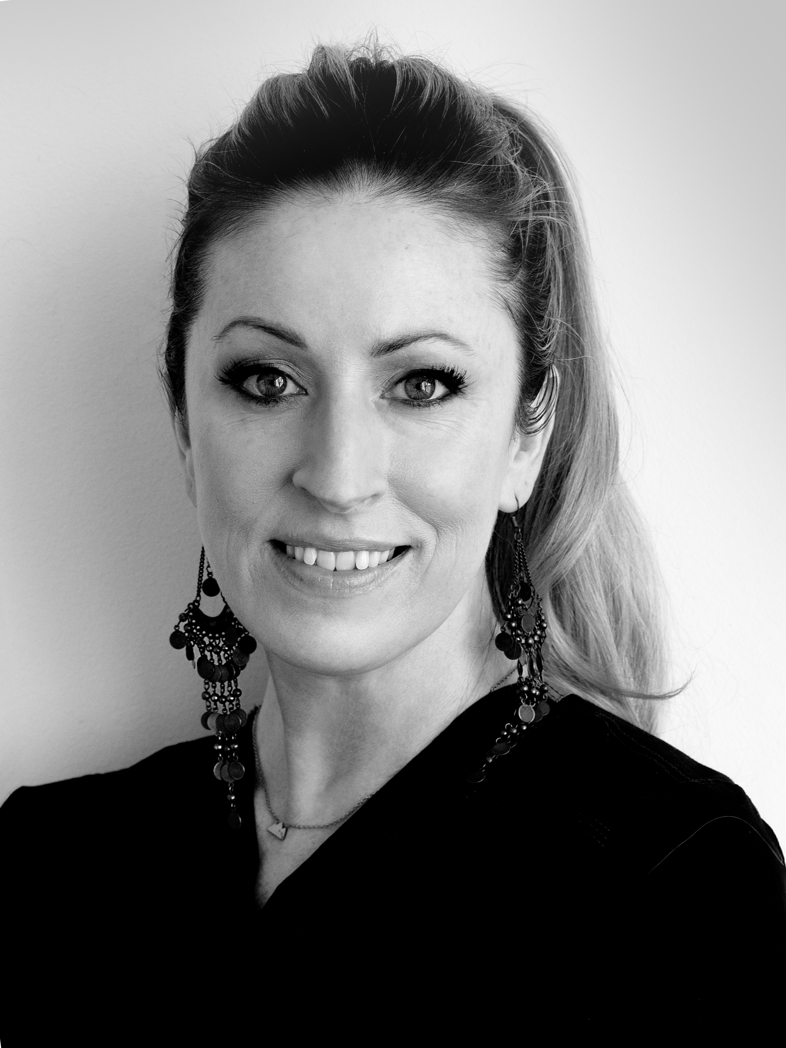 Black and white portrait of a person with long hair, hand touching hair, dim lighting.