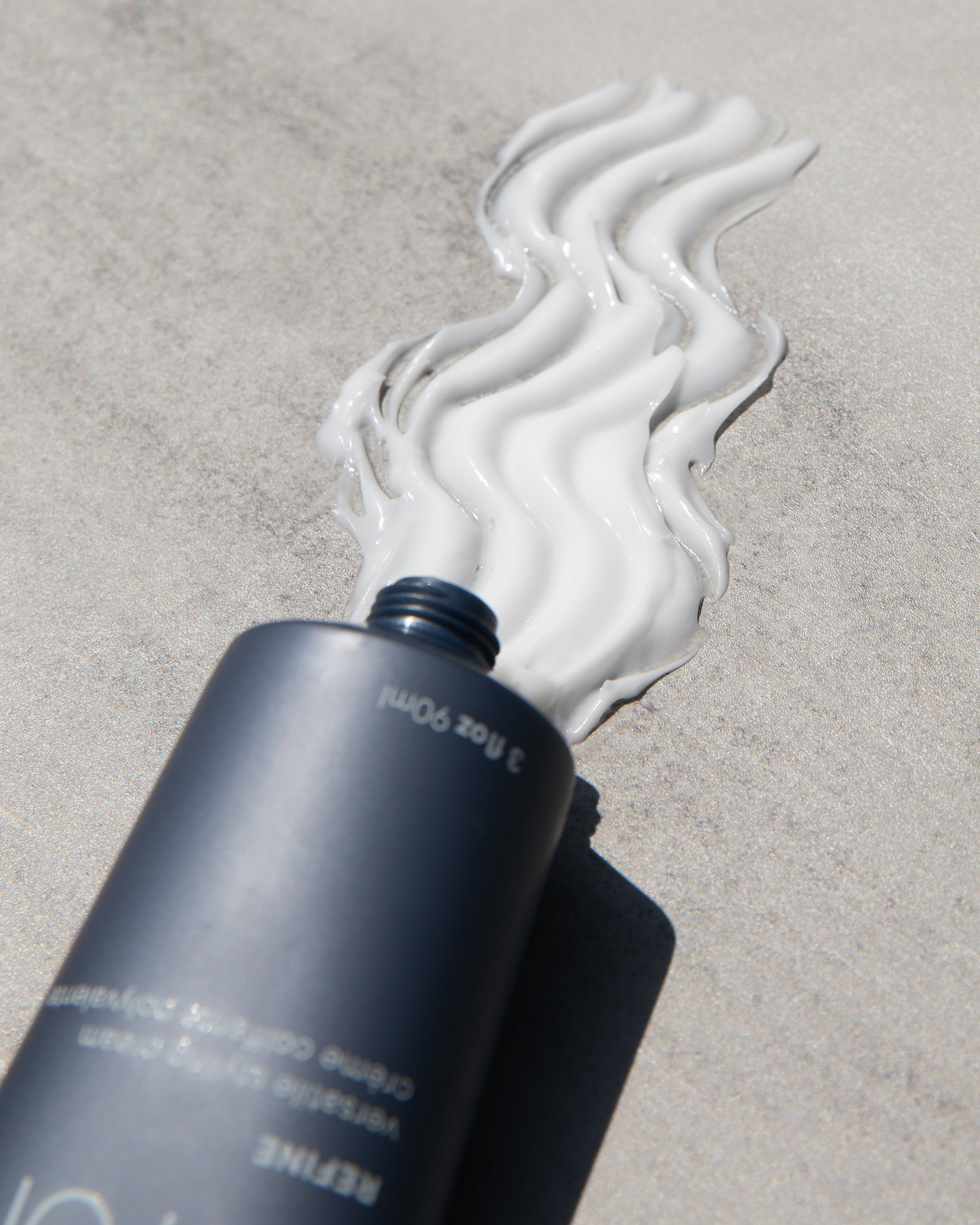 Open bottle of cream spilling onto surface, forming wavy pattern. 1816 House of Beauty, Spa and Salon Bedford Massachusetts.