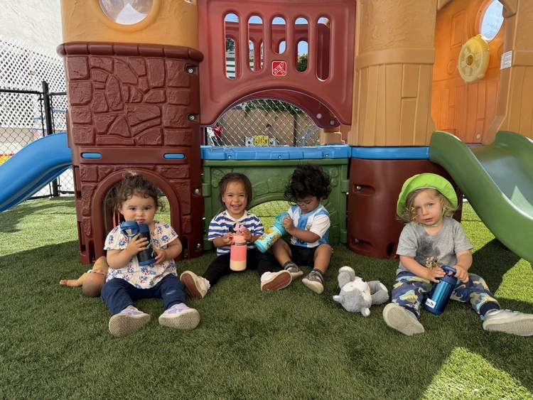 Toddlers sitting together in front of the playhouse