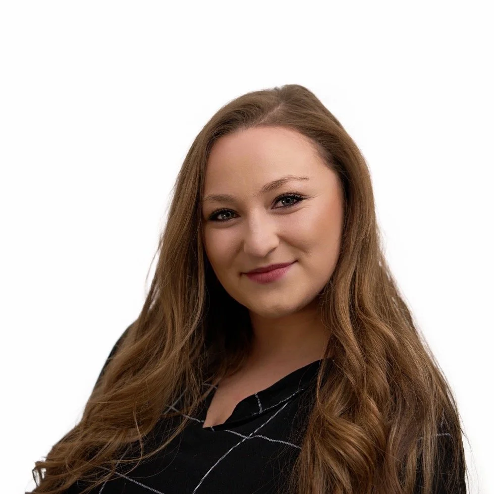 A friendly administrative assistant, with long, wavy brown hair, wearing a black top with white lines, smiling warmly against a white background.