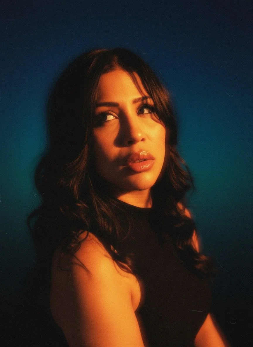 A woman with dark, wavy hair looking to the side against a dark background.