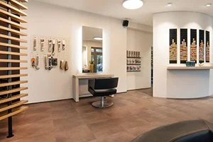 Innenraum eines modernen Friseurs mit Wanddekoration und Produkten wie z.B. Haarpflegeprodukte und Extensions auf Regalen. Der Friseur Salon befindet sich in Bad Oeynhausen und heißt HairClub.