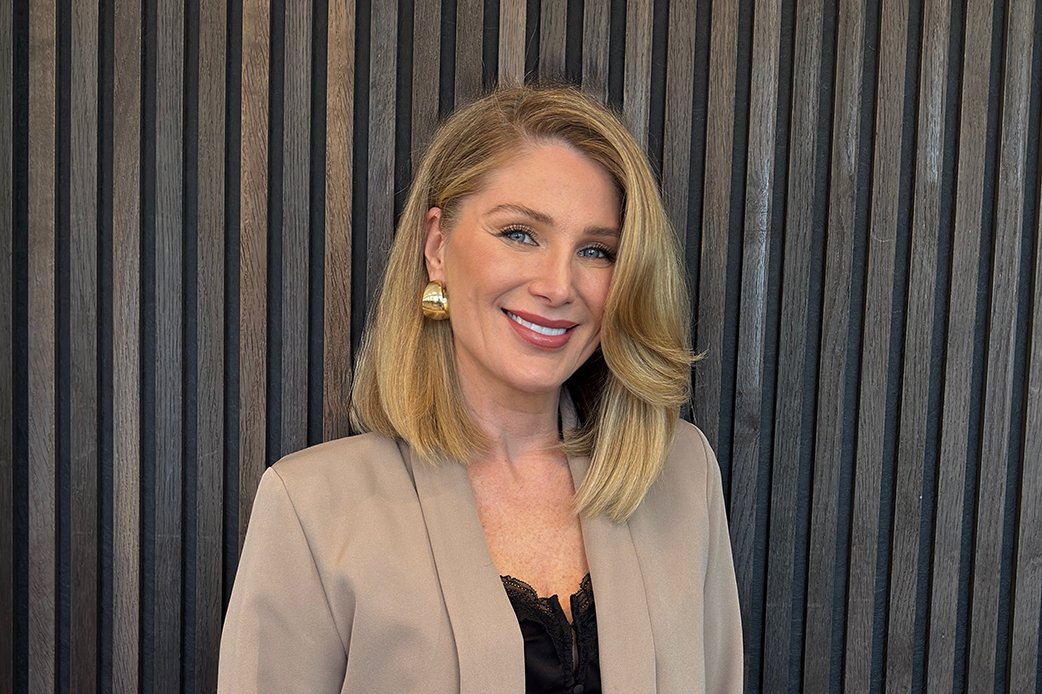 Eine lachende Frau mit blonden, schulterlangen Haaren, goldenen Ohrhängern und einem beigen Blazer vor einer Holzvertäfelung. Denis Sabur Co-CEO und Gründerin von HairClub Bad Oeynhausen, zertifizierte Epigenetik-Coachin und Friseur-Obermeisterin.