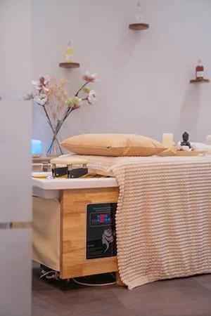 Ein gemütliches Zimmer mit einer Massageliege, einem Haarwaschbecken, Dekorationen, und Wandregalen. HeadSpa im HairClub Bad Oeynhausen, Kopfmassage, Lymphmassage im Gesicht. Regt die Durchblutung der Kopfhaut. Friseursalon.