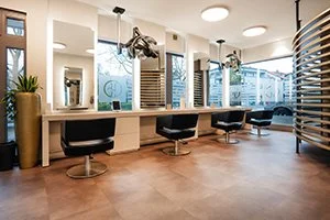 Friseursalon in Bad Oeynhausen HairClub, mit Sitztischen, Spiegeln und Haartrocknern, große Fenster, Holzfußboden, moderne Innenausstattung.