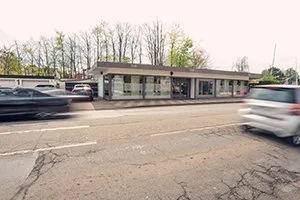 HairClub Bad Oeynhausen von außen, Autos fahren schnell vorbei. Weserstraße 1 gegenüber des Wear-Valley-Platz in der Stadt.