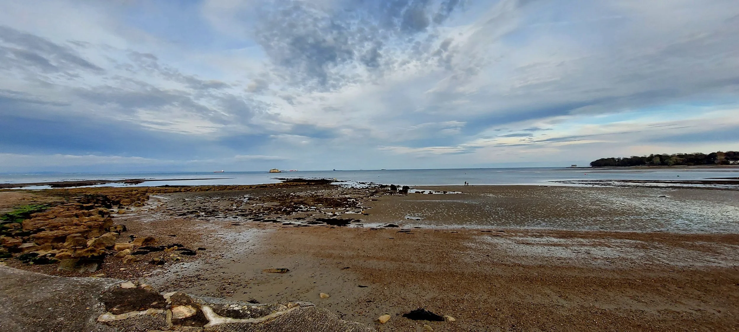 Rocky beach at low tide with blue cloudy sky in the background.