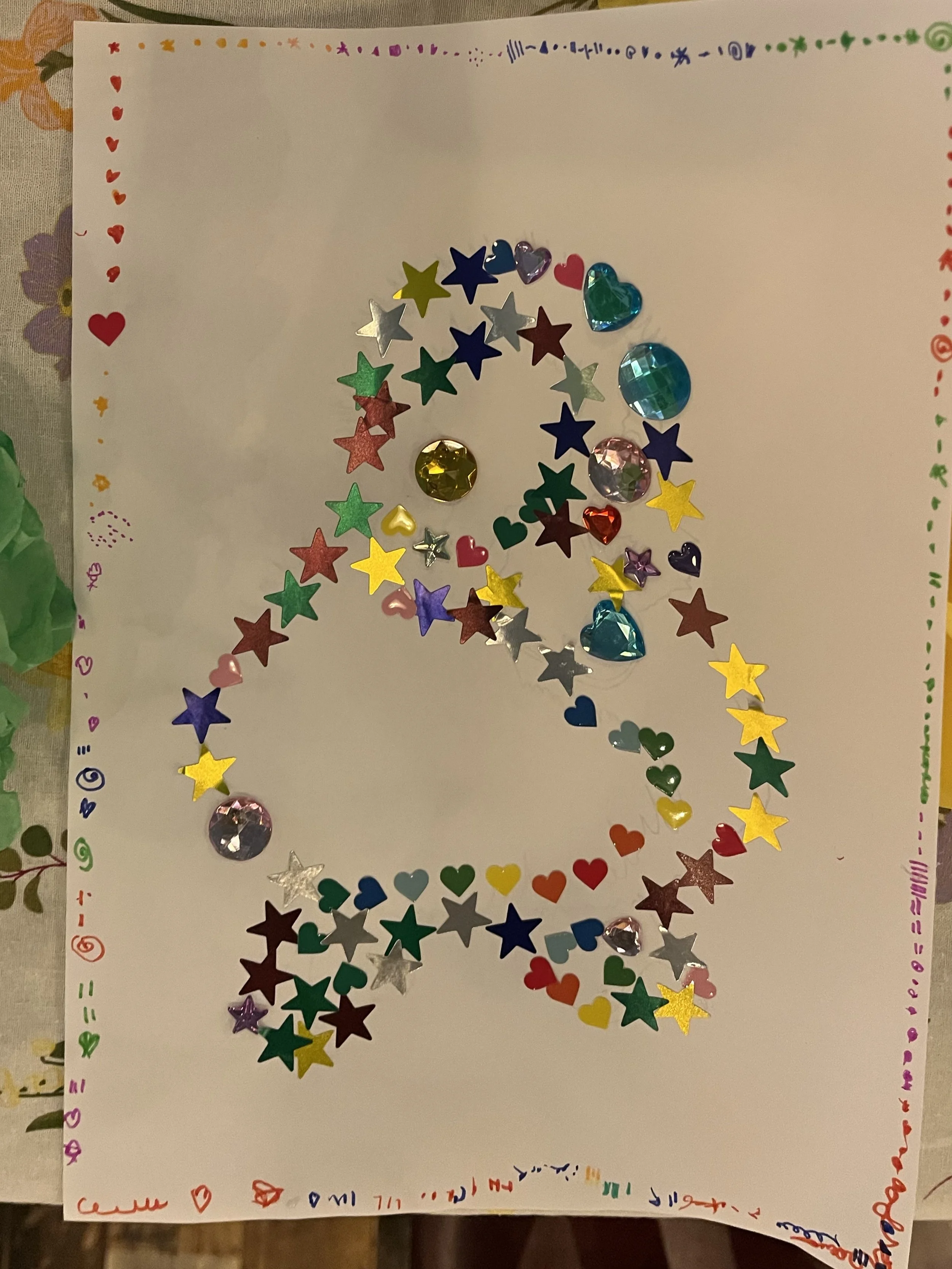 Example of the crafts, some of the children made today. Embellished paper made with Star Stickers and Plastic Jewels, including a Felt Tip Marker Border. (2026).
