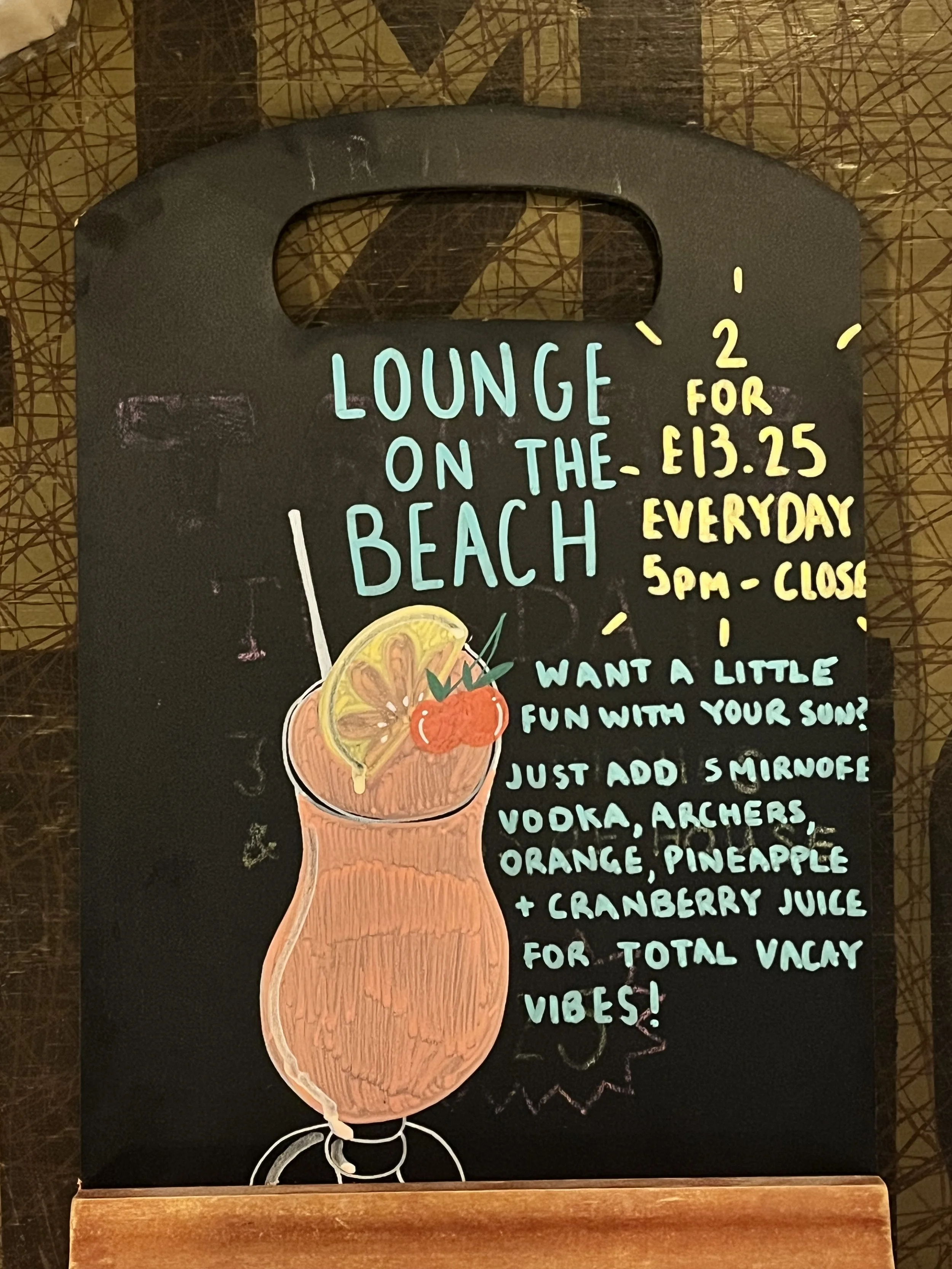 A4 sized Chalkboard promoting 'Lounge on the Beach Cocktails and the 2 for £13.25 deal. Hand Drawn text + image using Posca Markers (2025).