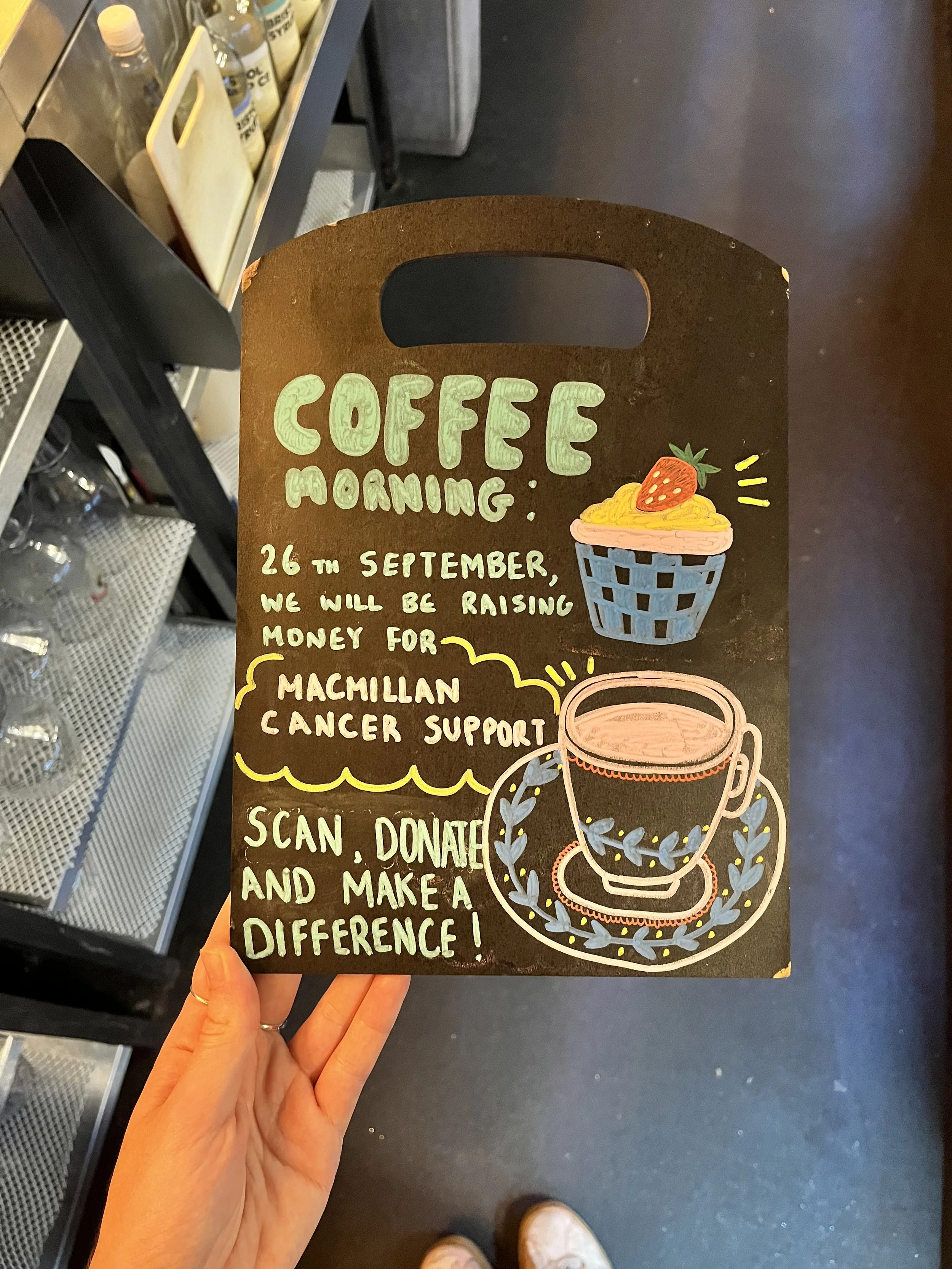 A4 sized Chalkboard promoting 'Macmillan Coffee Morning Event'. Hand Drawn text + image using Posca Markers (2025).