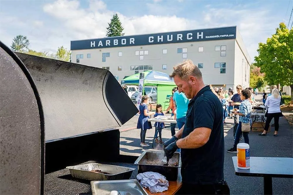Man grilling meat at an outdoor event at Harbor Church