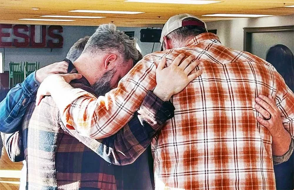 Men huddled in a circle praying together