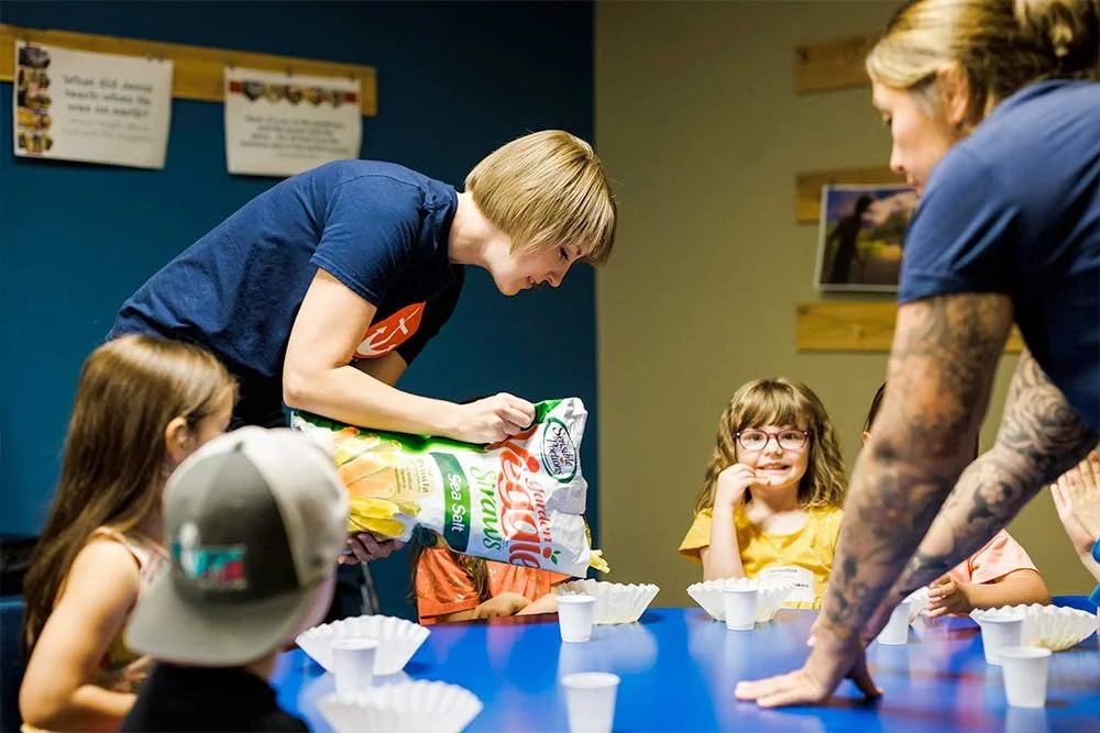 Adult helpers feeding snacks to preschool children