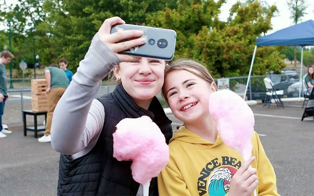 Two girls eating cotton candy and taking a selfie