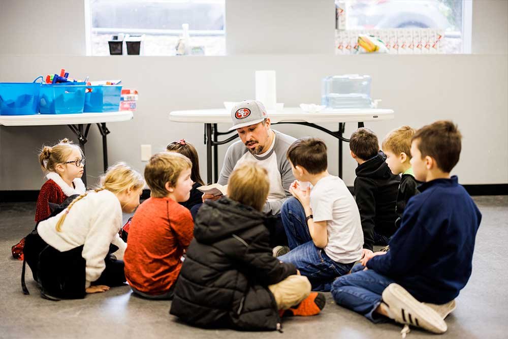 Man sitting on floor teaching children