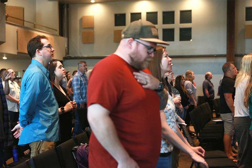 Man bowing head in worship at Harbor Church
