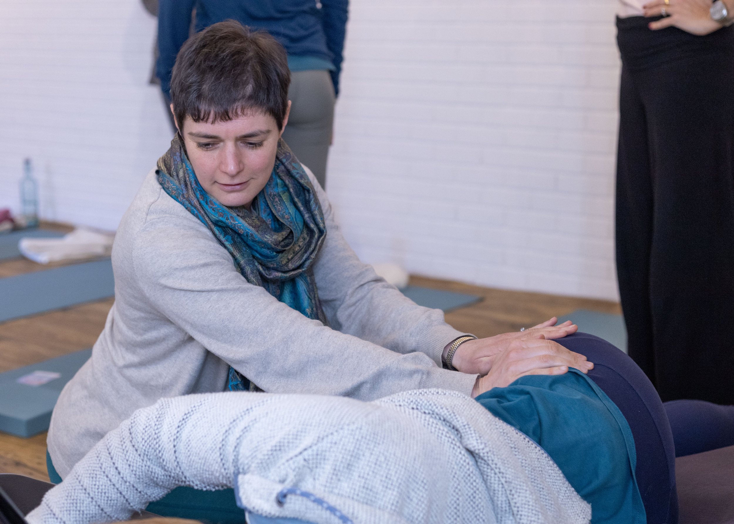 A woman practicing pelvic manipulation on a person lying on their side during a preparing for birth training session.
